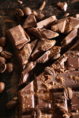 Chopped bar of chocolate on wooden background