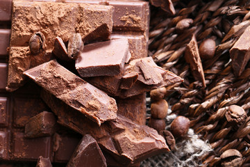 Chopped bar of chocolate on wicker mat background