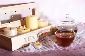 Composition with tea in cup and teapot and candles