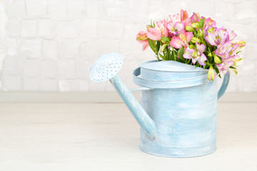 Fototapeta premium Beautiful bouquet of freesias in watering can in room