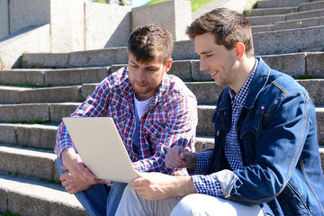 Happy students sitting on stairs in park