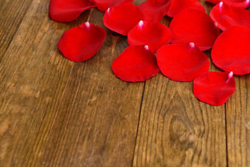 Beautiful petals of red roses on wooden background