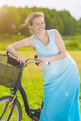 Fototapeta na wymiar Young Caucasian Blond Laughing Outdoors Standing Near Her Bicycl
