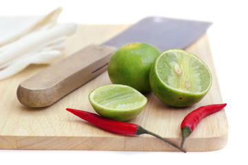 chillis and lime on chopping board and the knife isolated