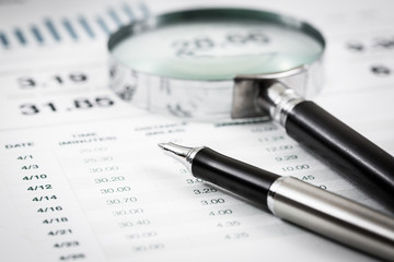 magnifying glass and pen over graph on table.Accounting