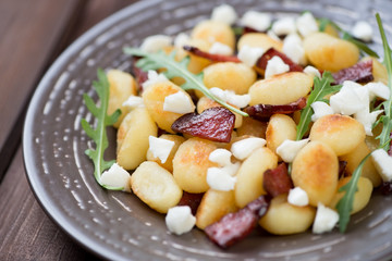 Fried gnocchi with cheese, meat and arugula leaves, close-up