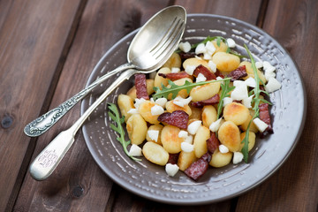 Fried gnocchi with meat, cheese and arugula leaves, studio shot