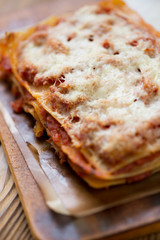Close-up of lasagna bolognese on a cutting board, vertical shot