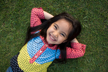 Little Asian child laying down on the lawn © RedcupStudio