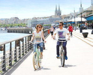 Cheerful couple riding bikes by sunny day - obrazy, fototapety, plakaty
