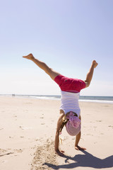 Deutschland,Ostsee,Mädchen (6-7 ) macht Handstand am Strand,Rückansicht