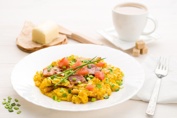 Scrambled eggs and bacon on white table