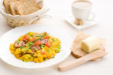 Scrambled eggs and bacon on white table