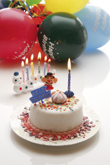 Geburtstagstorte mit brennenden Kerzen und Luftballons