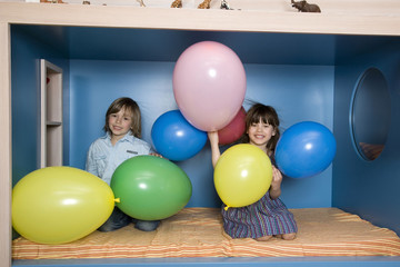 Boy (8-9) und Mädchen ( 6-7) spielen mit Luftballons,Lächeln,Portrait
