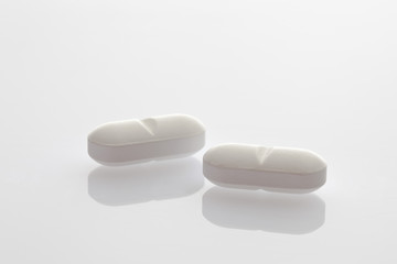 Zwei weiße Tabletten auf weißem Hintergrund