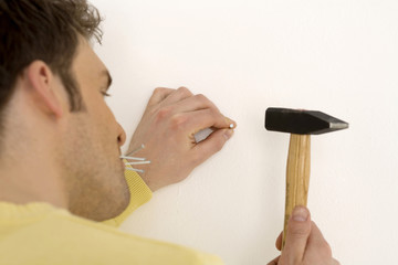 Man Hämmern Nagel in die Wand,close-up