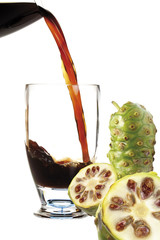 Noni-Saft in Glas , frische Früchte daneben