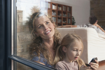 Deutschland,Köln,Mutter und Tochter ( 6-7 ) sitzen am Fenster,der Vater im Hintergrund,Portrait