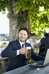 Deutschland,Bayern,Oberbayern,Junger Geschäftsmann im Biergarten hält Steinkrug,Lächeln,Portrait