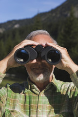 Österreich,Karwendel,älterer Mann schaut durch Fernglas,Portrait