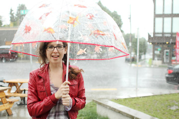 Young woman with umbrella standing in the rain.