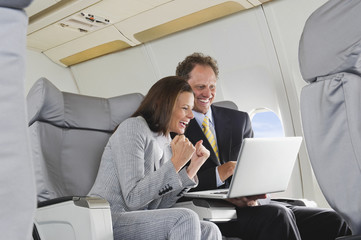 Deutschland,Bayern,München,Geschäftsmann und Geschäftsfrau auf Laptop in der Business Class...