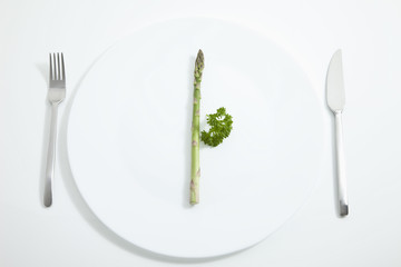 Spargel in Platte mit Gabel und Messer auf weißem Hintergrund