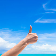 Closeup thumbs up on the beach background blue sky