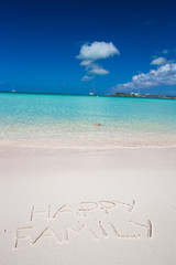 Fototapeta na wymiar Happy family written on tropical beach white sand