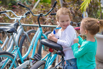 Fototapeta na wymiar Little adorable girls having fun near the bikes on exotic resort