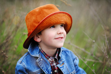 Happy smiling boy dressed in country style playing in the park