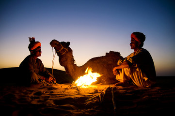 Indigenous Indian Men Resting By The Bonfire With Their Camel - obrazy, fototapety, plakaty