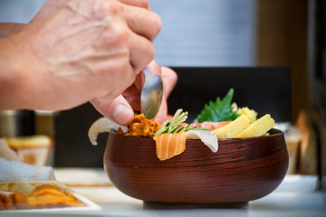 Hands of a Japanese Chef make a bowl of Sushi
