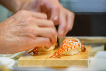Hands of a Japanese Chef make a bowl of Sushi