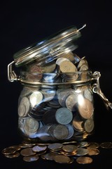 Coins in a glass jar on a black background