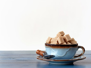 Brown sugar cubes in cup on wood with white background