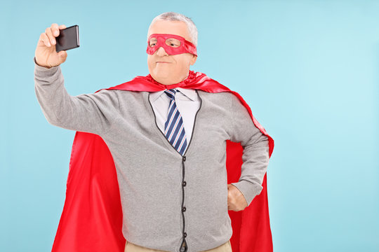 Mature man in superhero costume taking selfie
