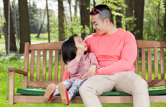 Asian Family Sitting On A Swing