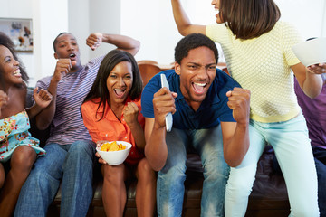 Group Of Friends Sitting On Sofa Watching TV Together