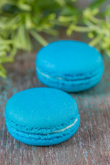 Light blue French macarons with buttercream on a wooden table.