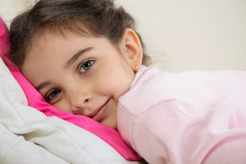 Cute hispanic girl lying in bed