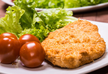 Fried battered chicken breast fillet  with lettuce on the plate