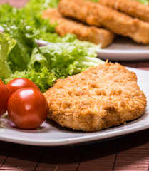 Fried battered chicken breast fillet  with lettuce on the plate
