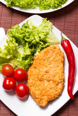Fried battered chicken breast fillet  with lettuce on the plate