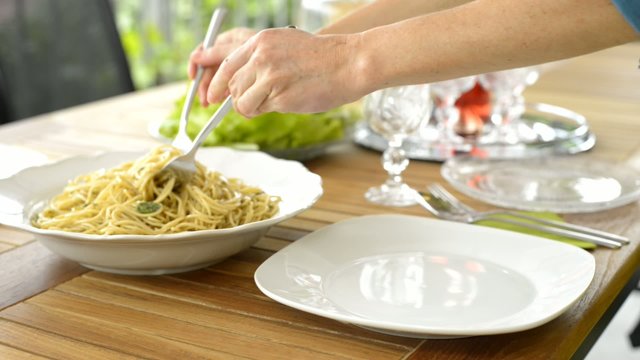 Woman Serving spaghetti with pesto sauce on plate