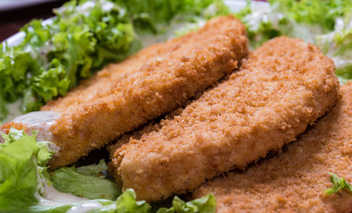 Fried battered chicken breast fillet  with lettuce on the plate