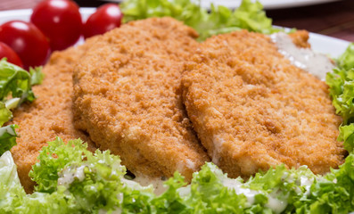Fried battered chicken breast fillet  with lettuce on the plate
