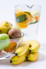 Lemonade with oranges and mint in glass jug on wooden table