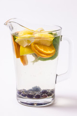 Lemonade with oranges and mint in glass jug on wooden table